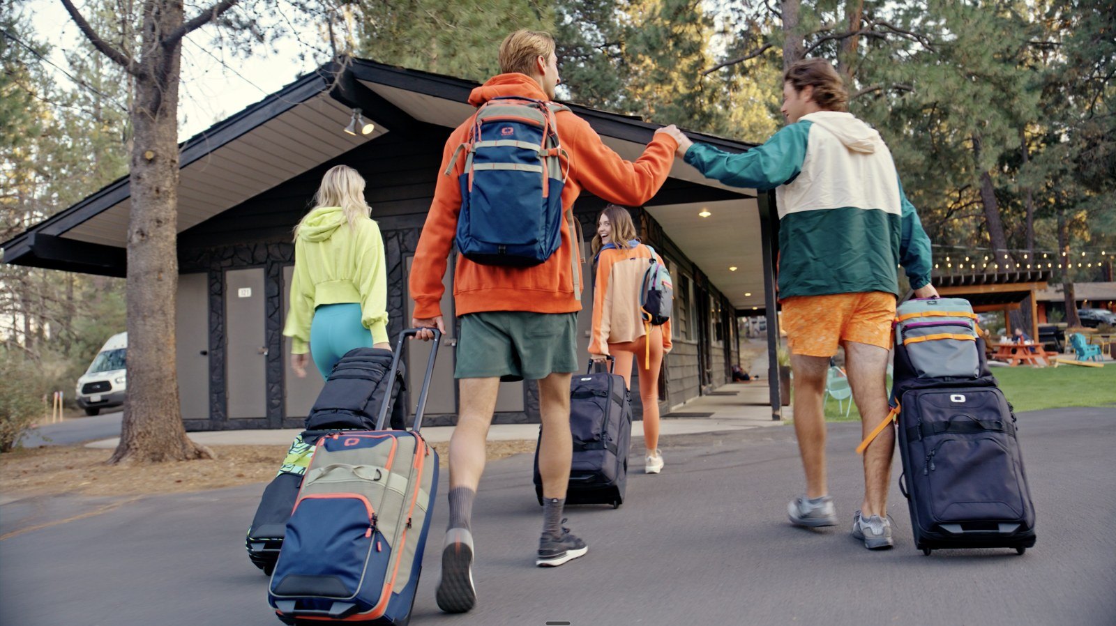 Video frame: friends rolling OGIO luggage toward a lodge