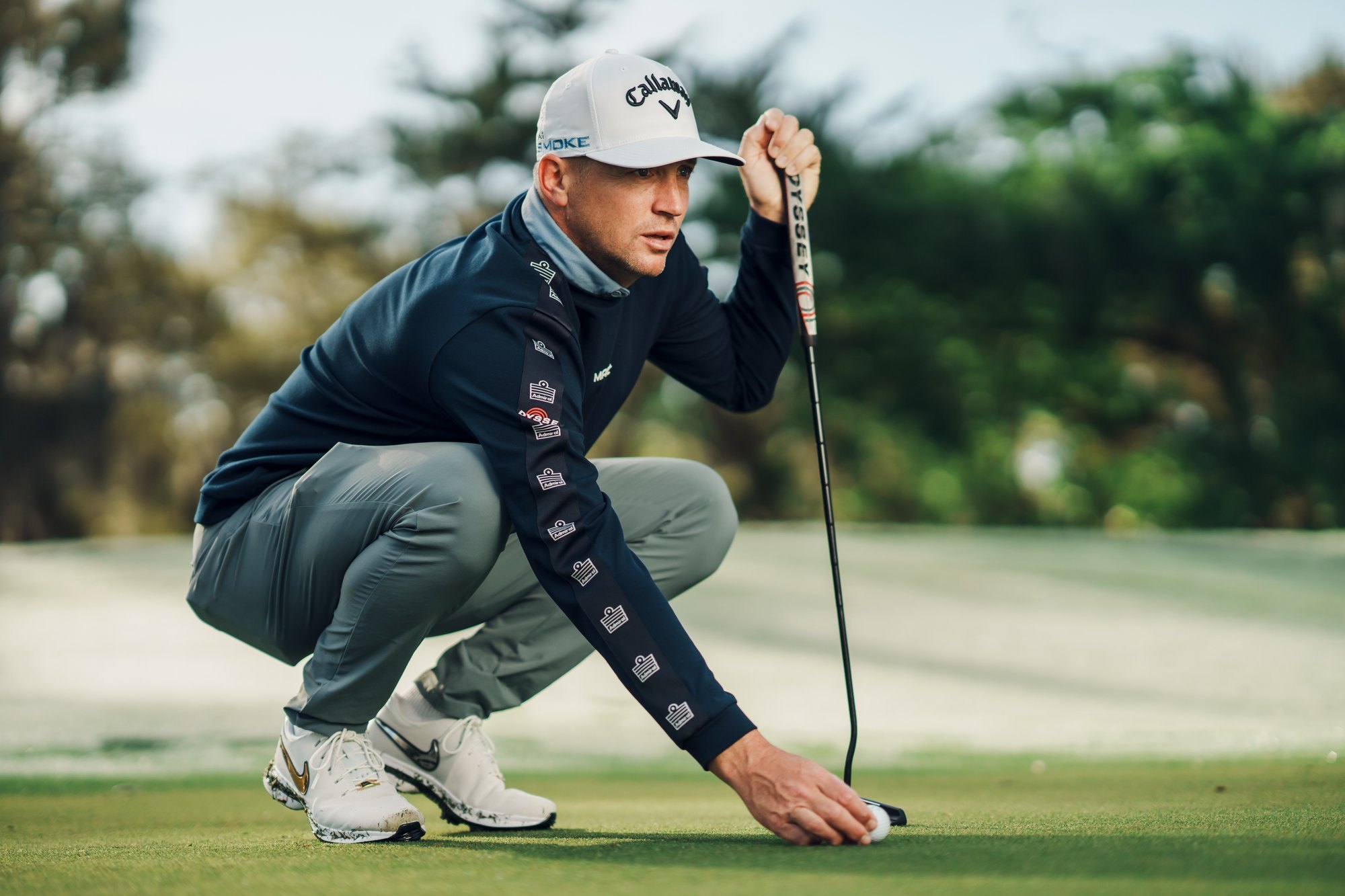 Tour player crouched with putter